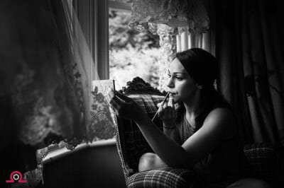 Bride applying her makeup in the window -Larmertree Wedding