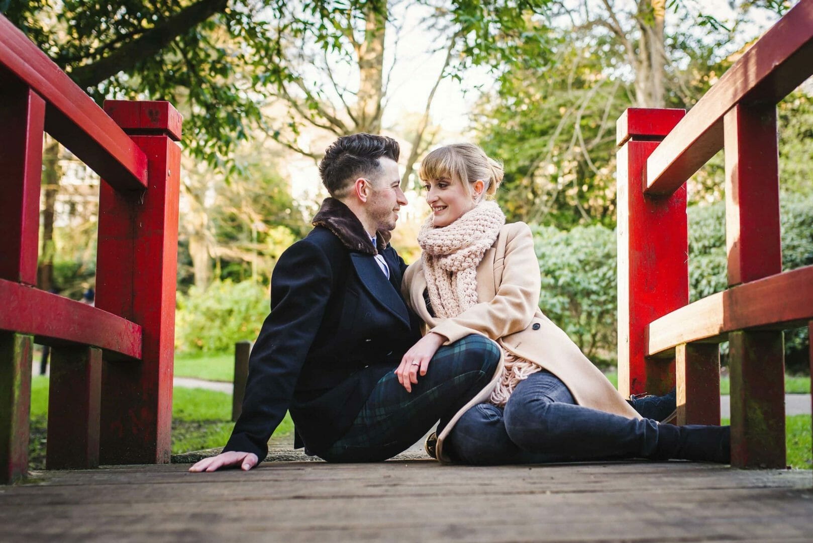 Couple sit on the red Monet bridge in Bournemouth gardens