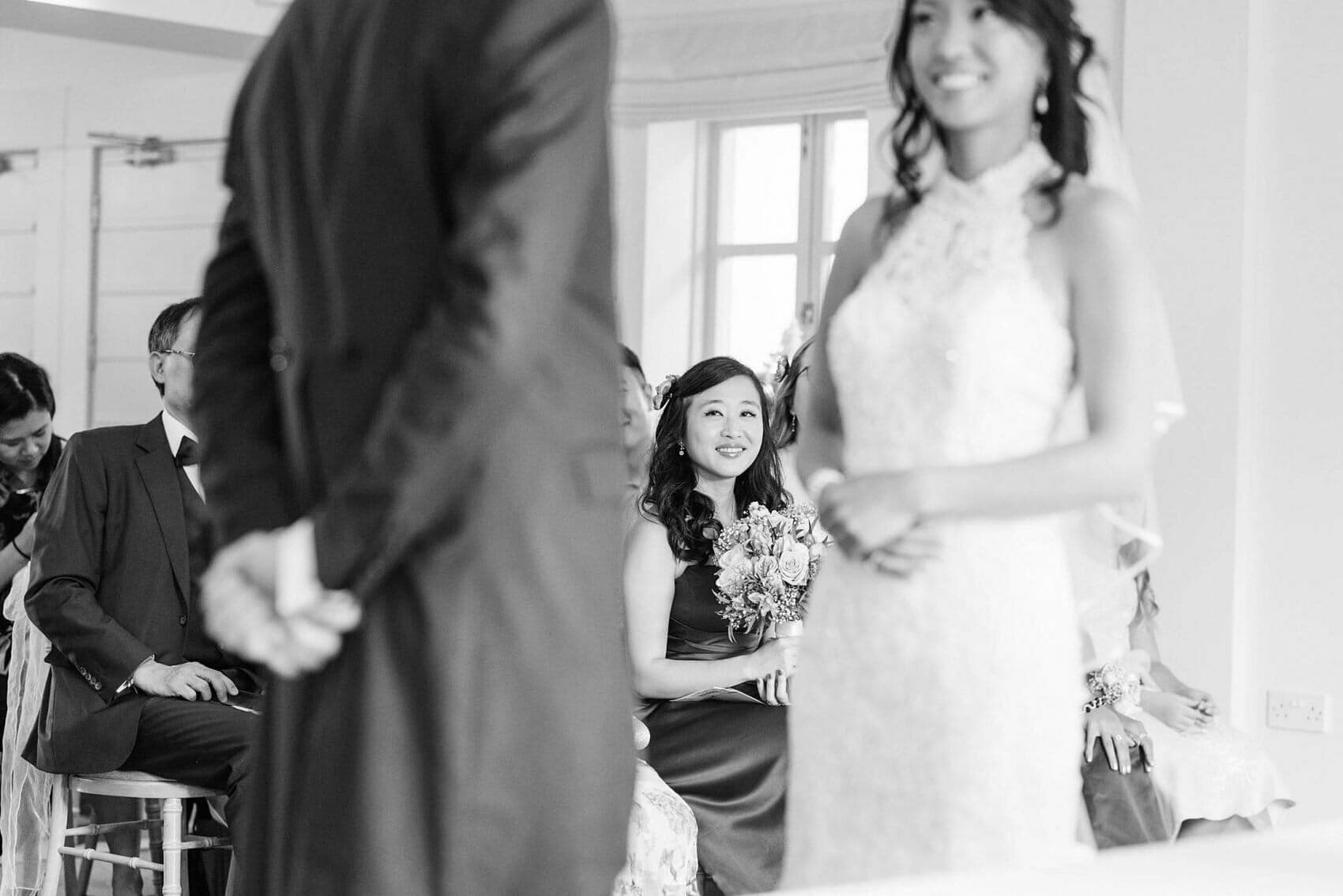 Bridemaid smiles at couple in wedding ceremony