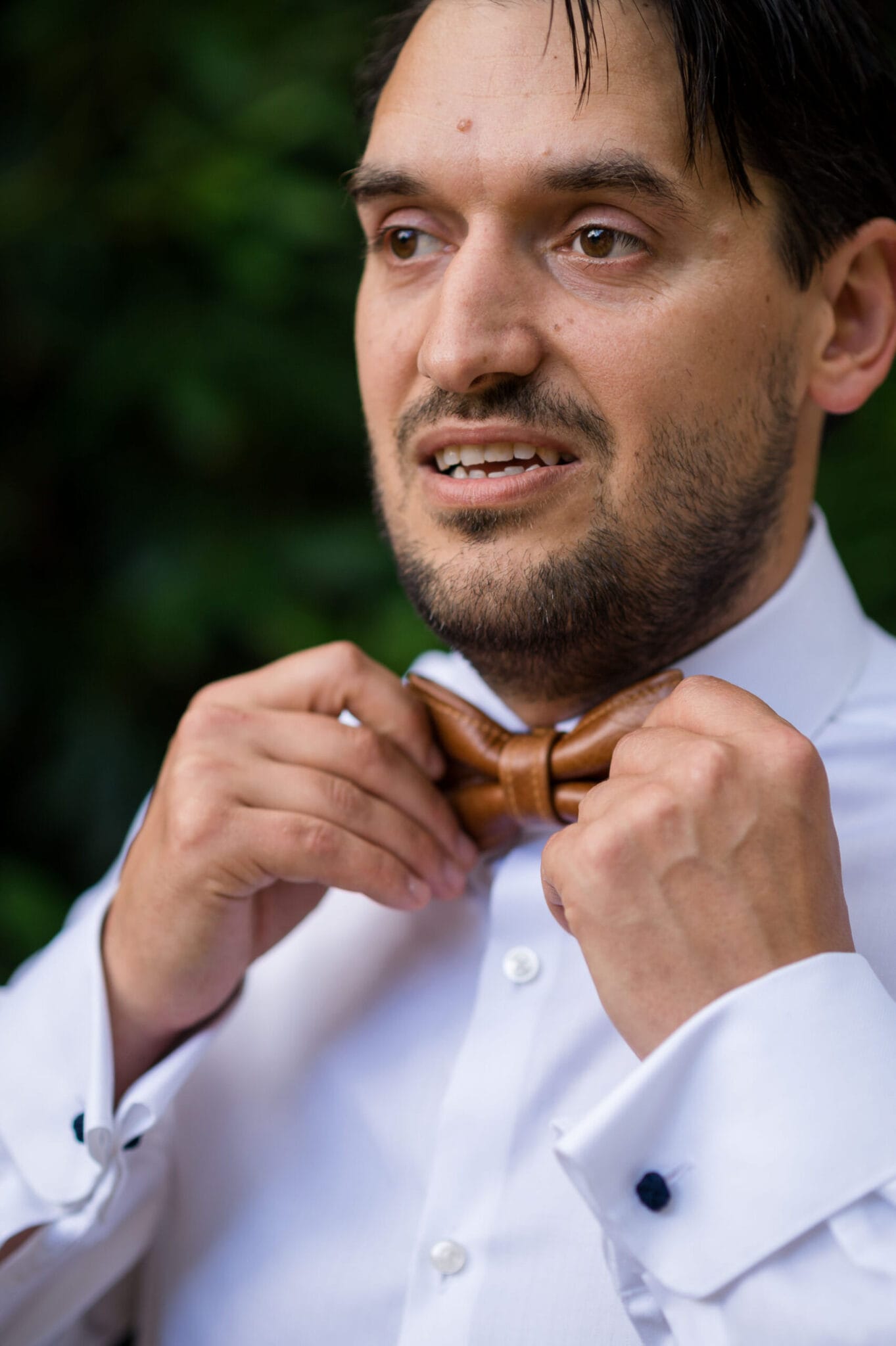 Groom adjusting bow tie at Weddings in the Wood