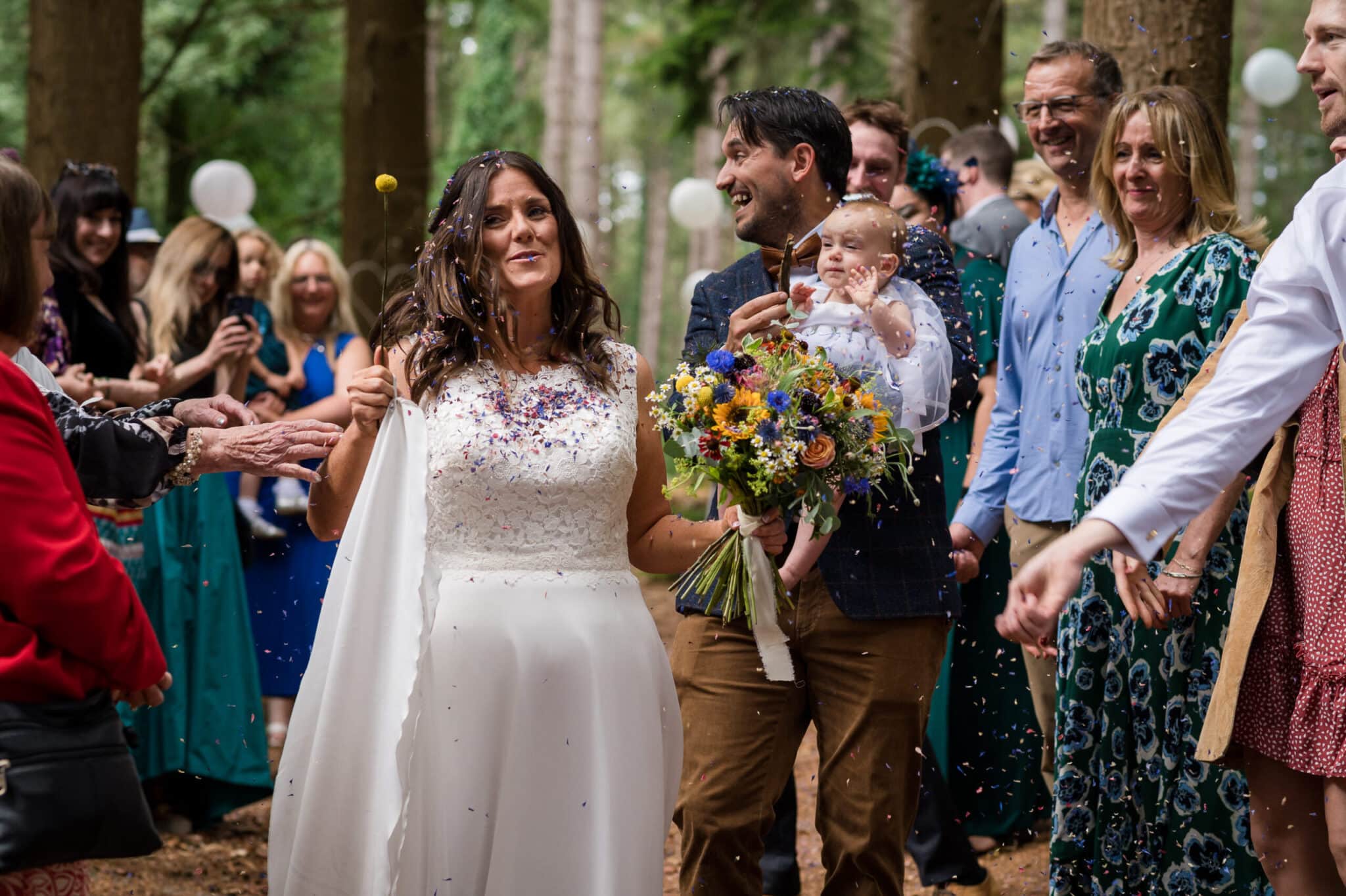 Bride and groom walk through confetti at Weddings in the Wood