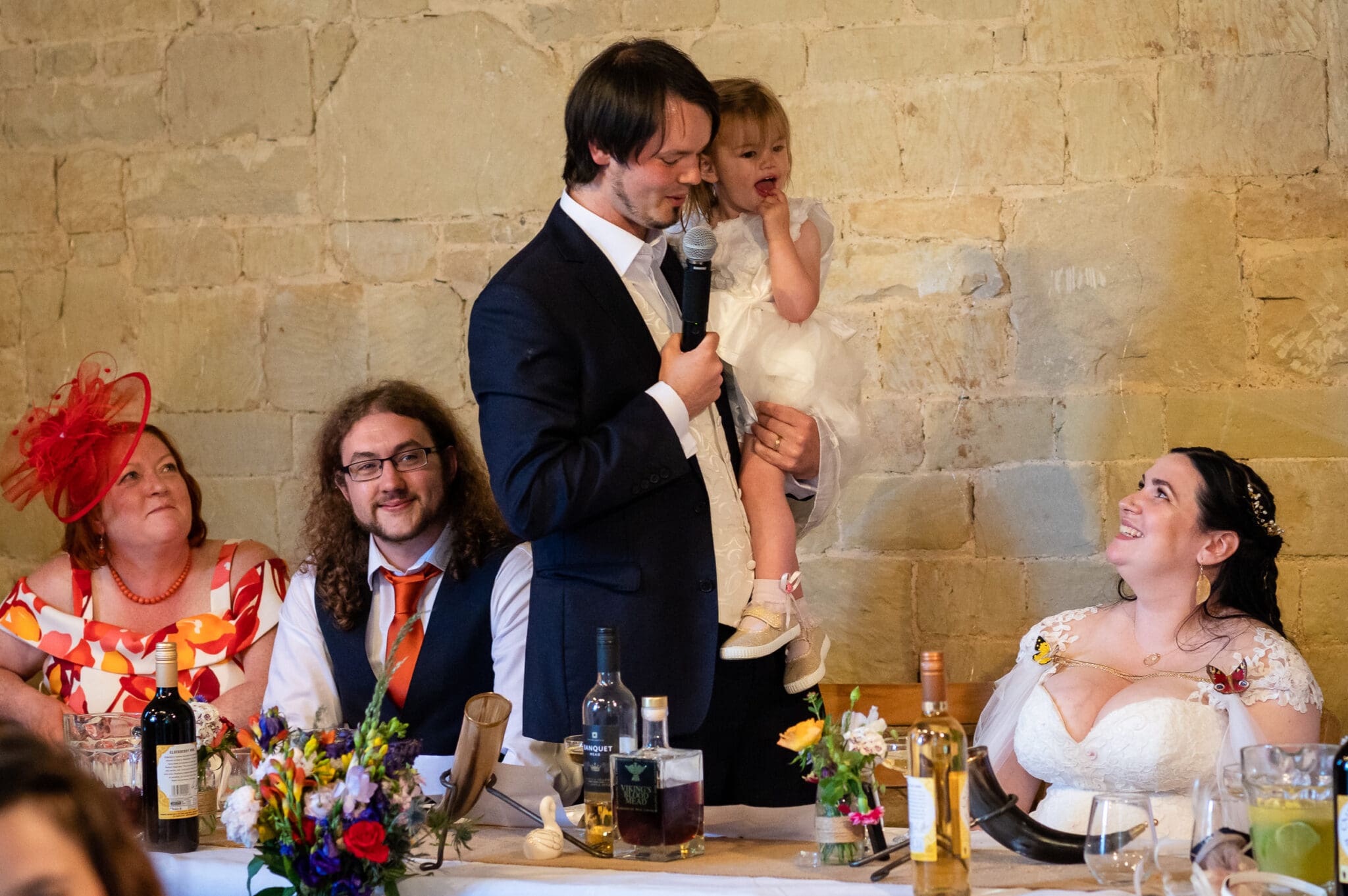 flowergirl cuddles groom during his speech at Ashley Wood Farm wedding
