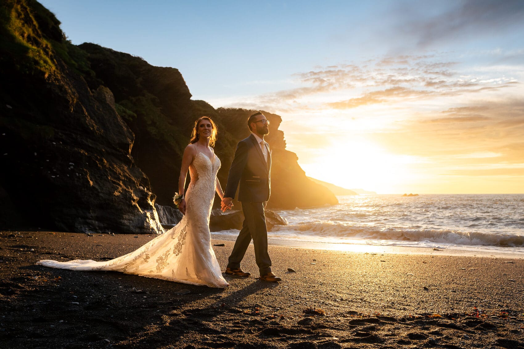 Bride and groom walking in the evening sunset at Tunnels Beaches Wedding venue