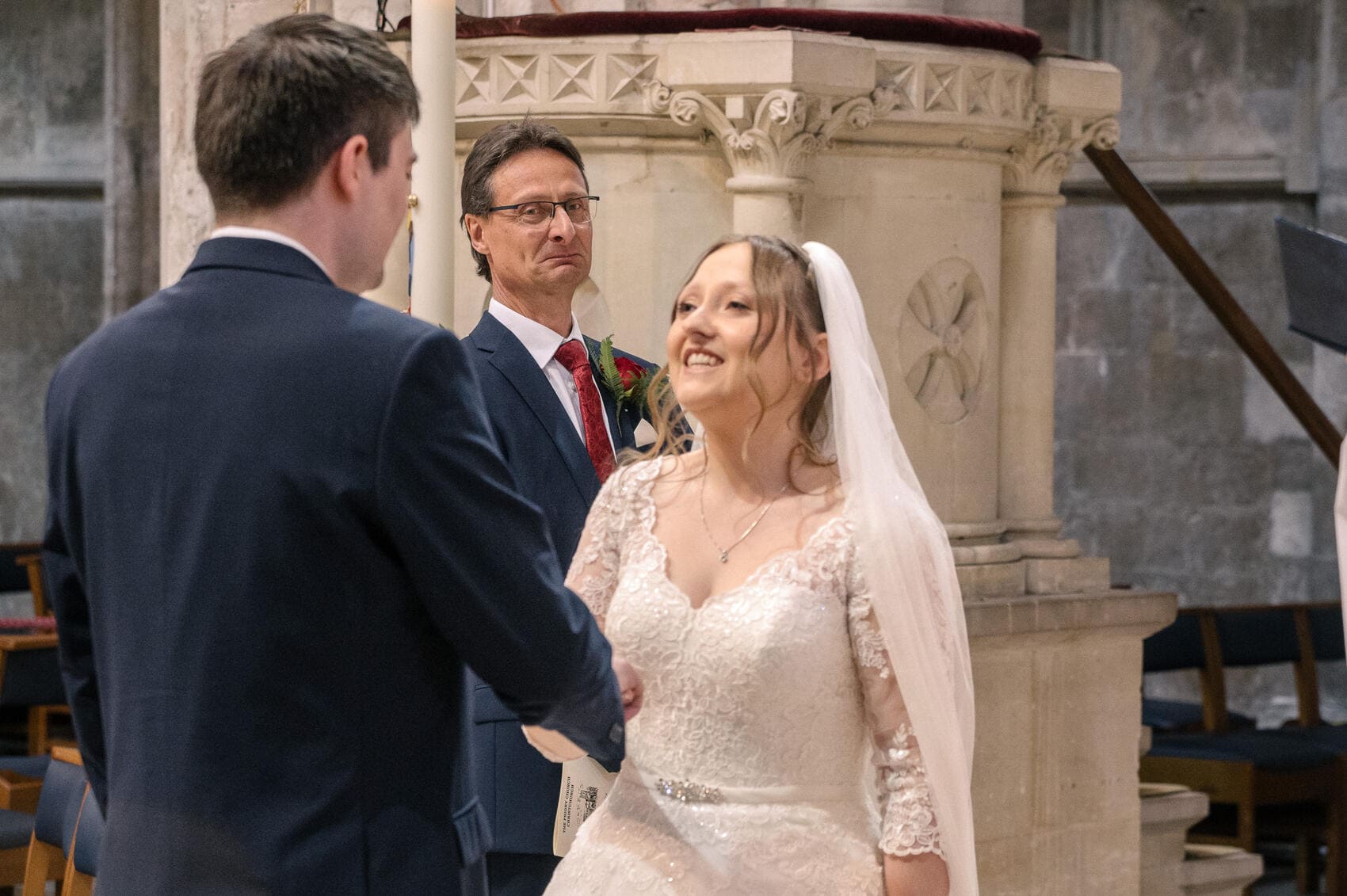 Father of the bride looks at couple in Christchurch Priory wedding ceremony
