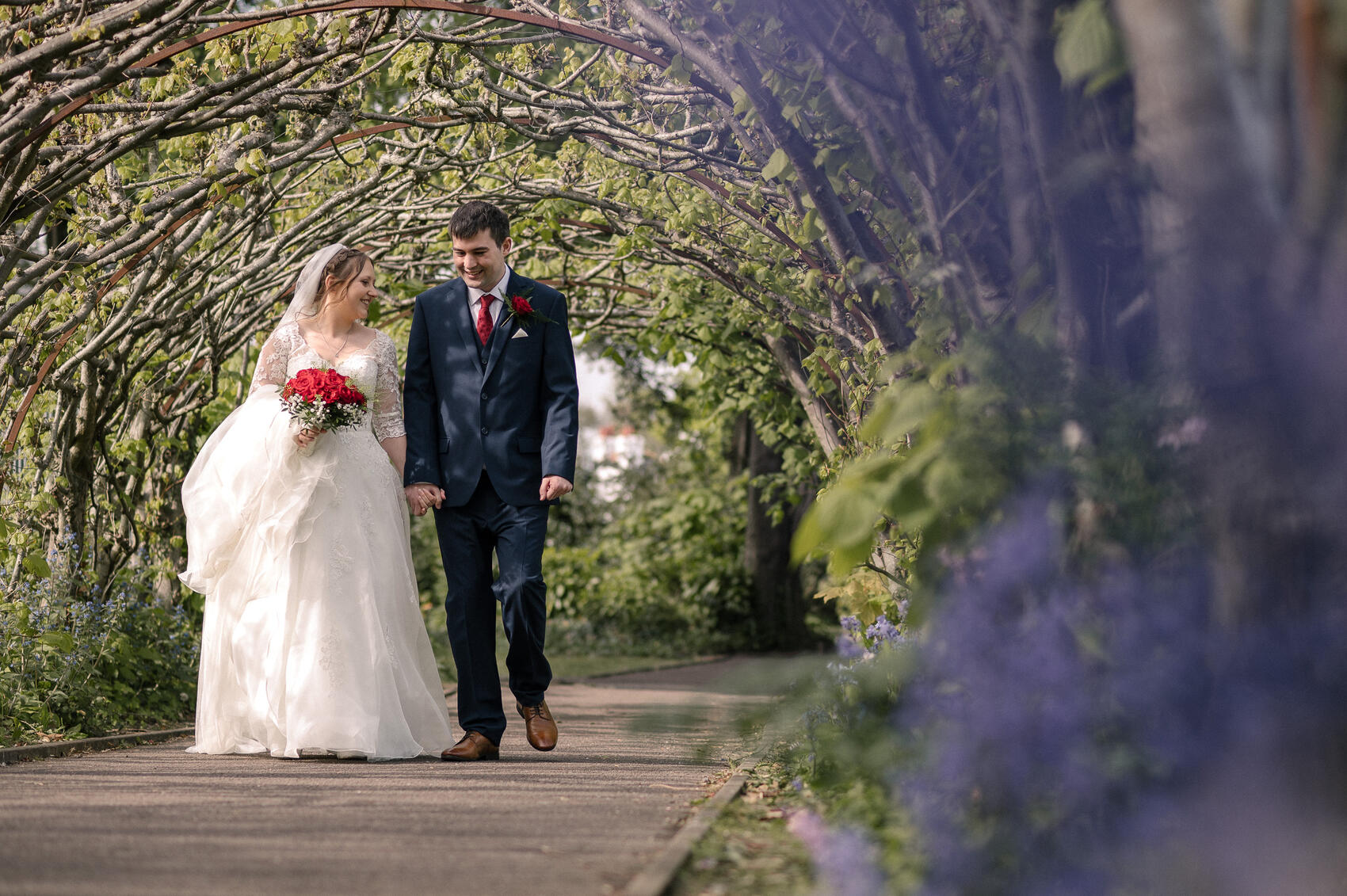 Bride and Groom Walking through the tunnel of trees near Christchurch Priory