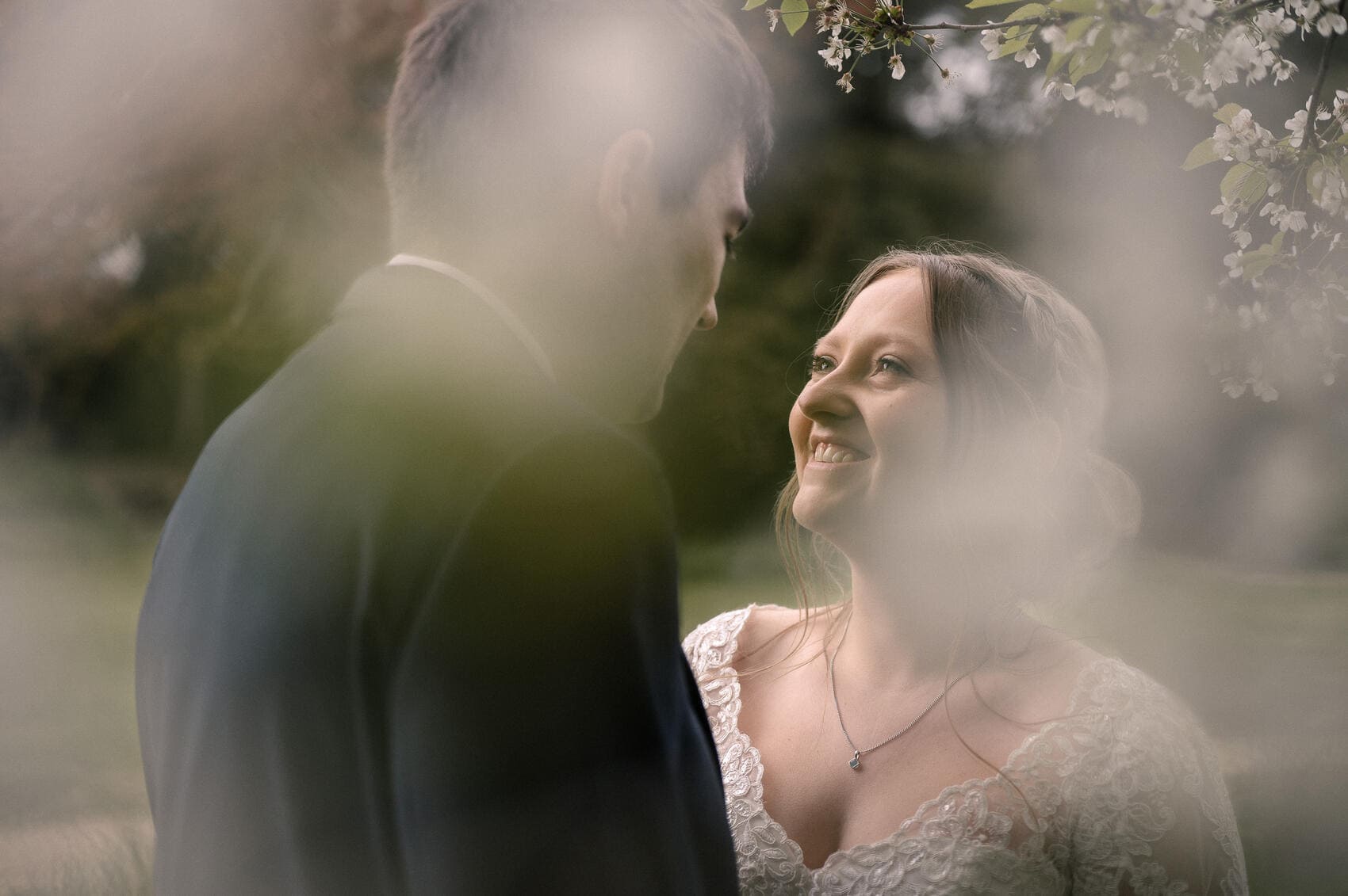 Bride smiles at groom through the trees at Highcliffe castle wedding