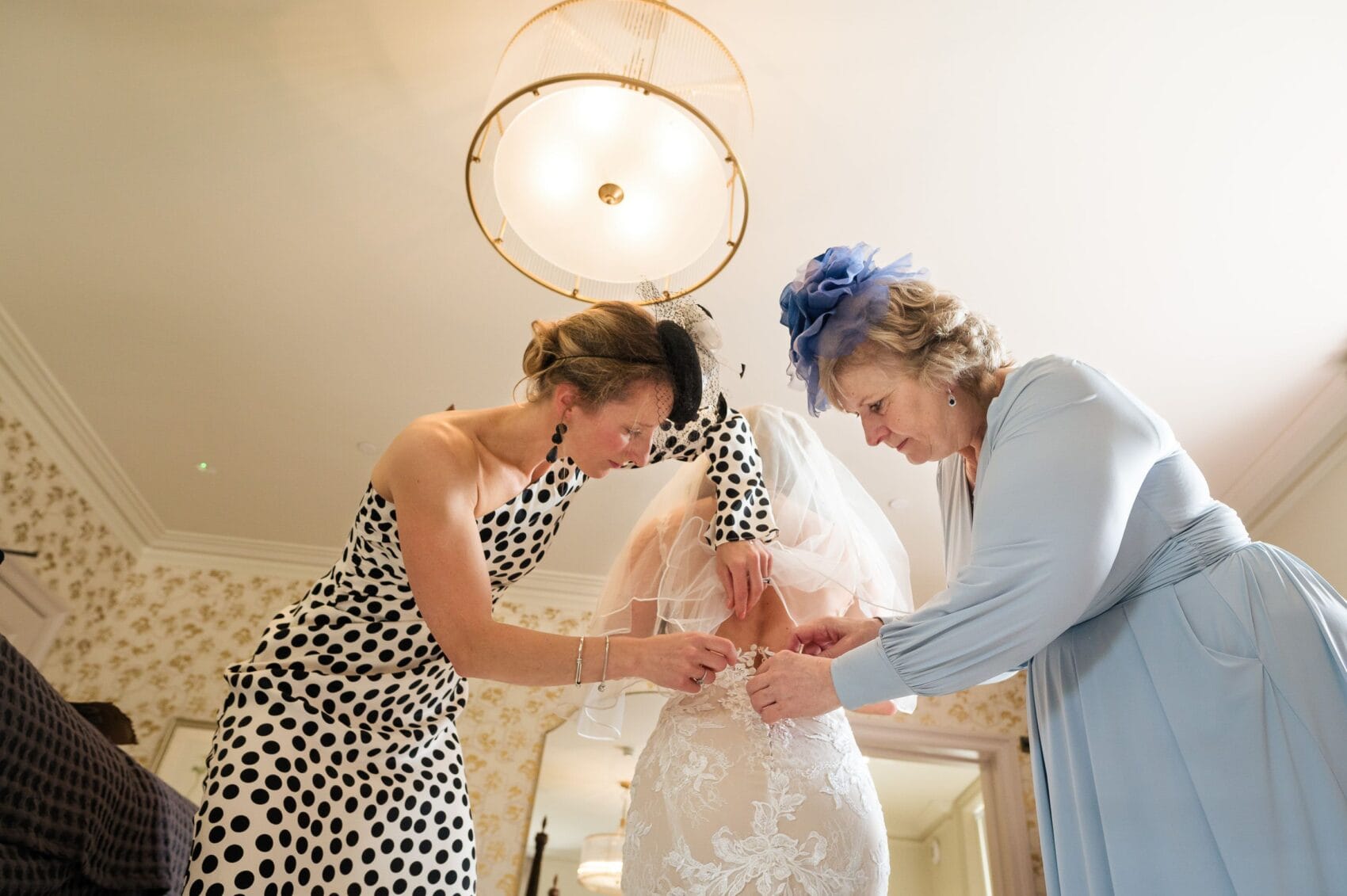 Mum and friend help do up the wedding dress