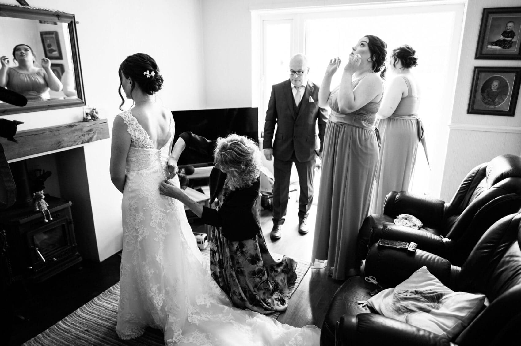 Emotional bridesmaid helping the bride with her dress before St Mary's Catholic Church wedding