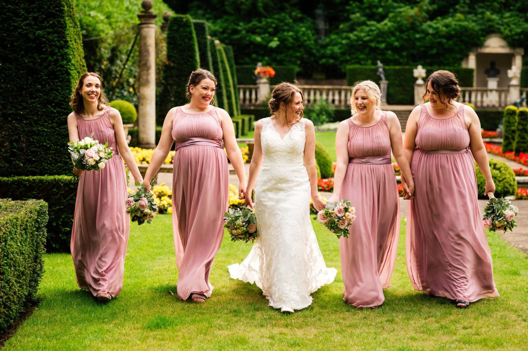 Bride walks with bridesmaids in Blush Pink dresses