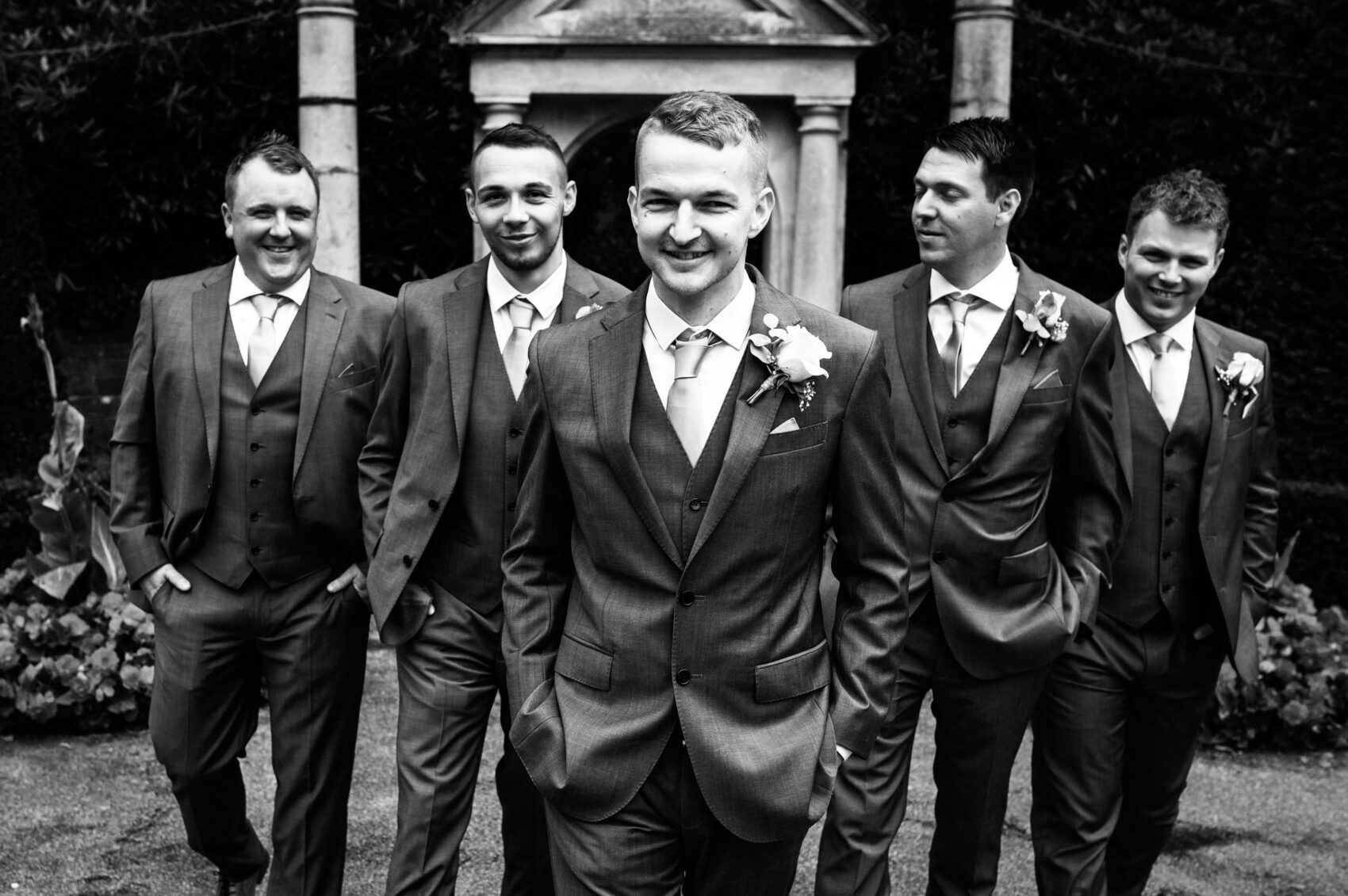 Grooms party walk in formation towards the camera in B&W