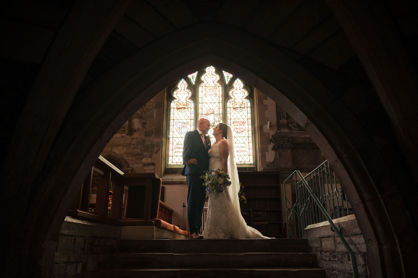 Bride and Groom by the stain glass window in the Wimborne Minster