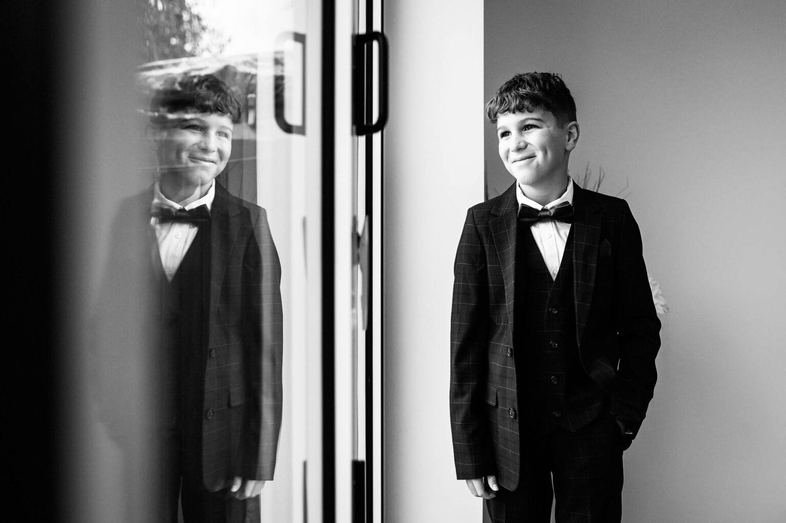 Paige boy in black and white standing by a window