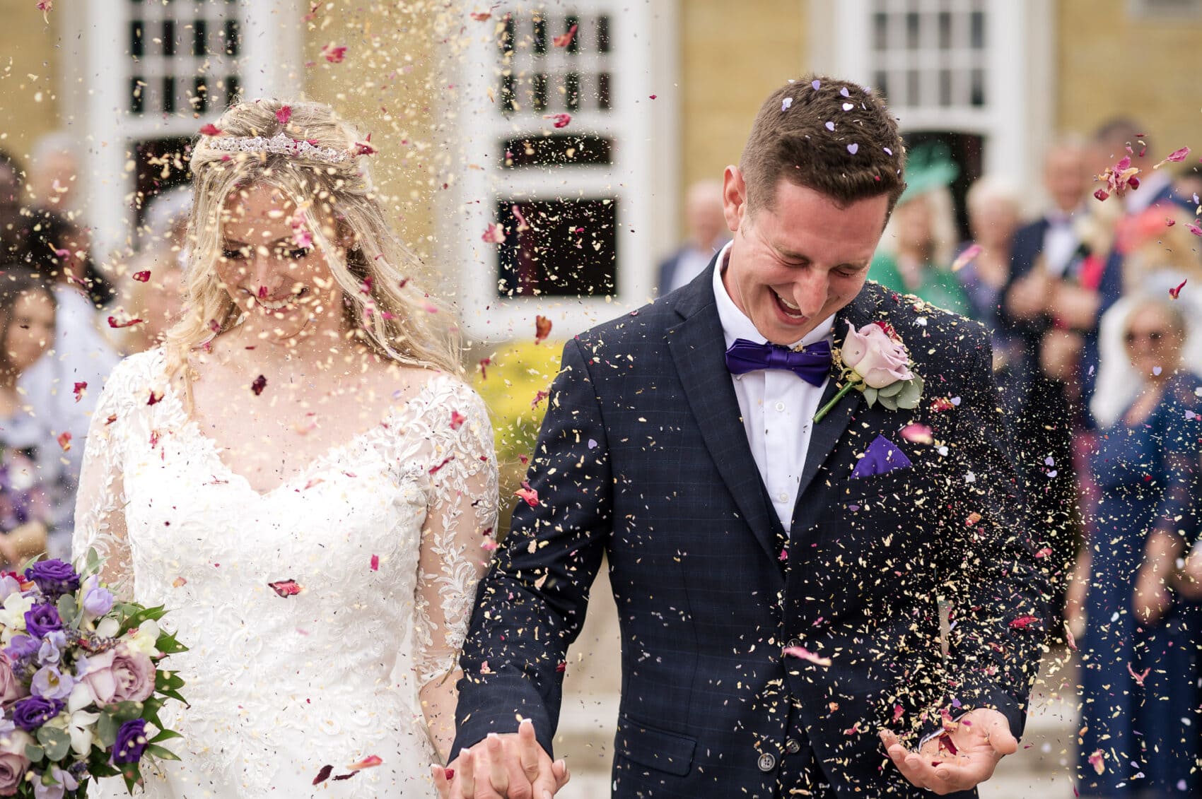 Bride and groom get a face full of confetti at their Chilworth Manor Hotel wedding