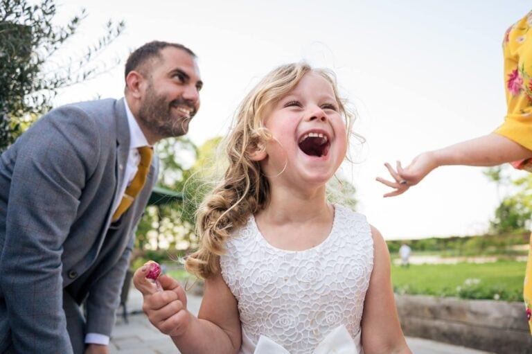 flowergirl laughing in white lace dress