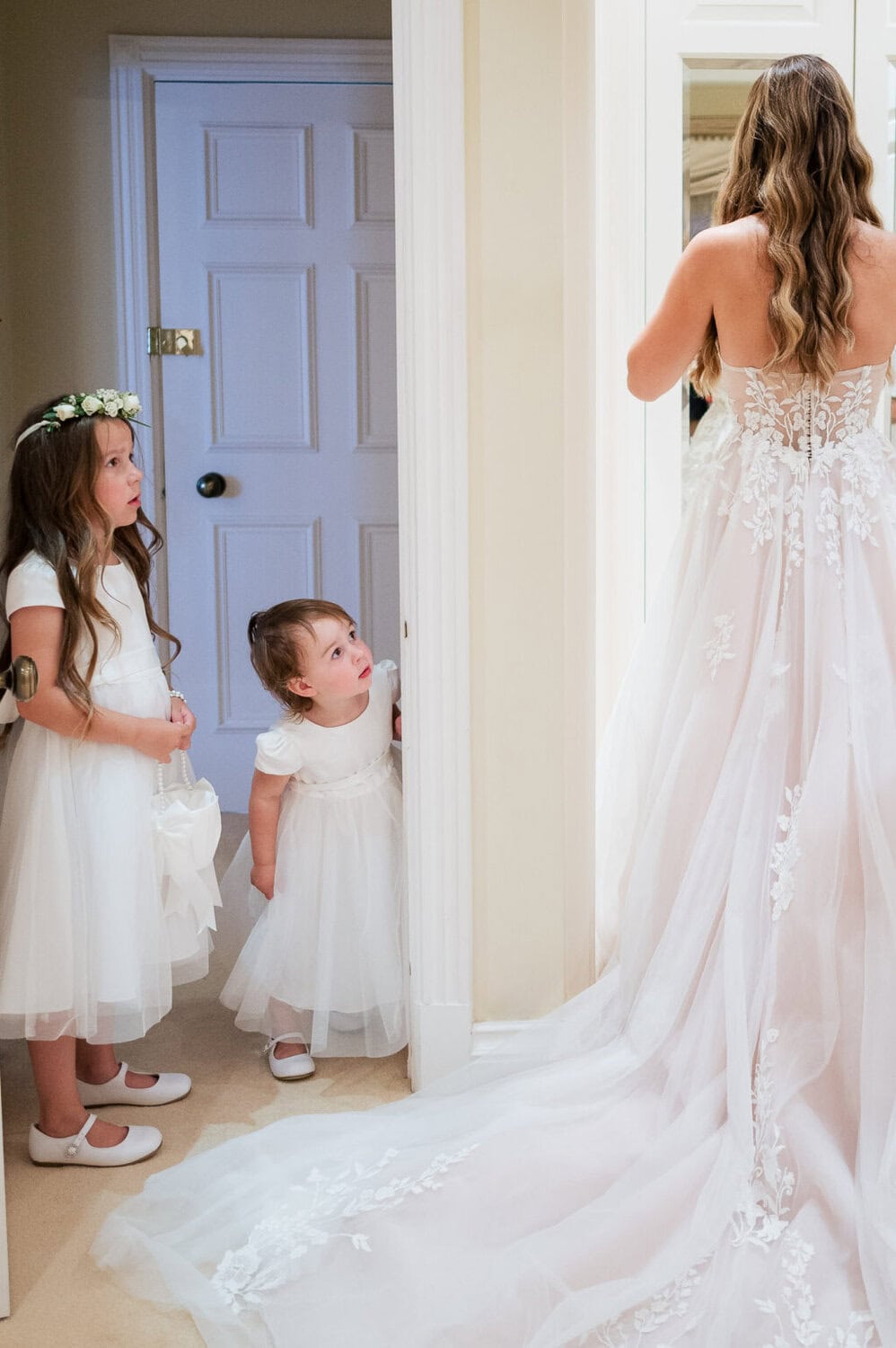 Flowergirl watches her mum finish puttin on her dress at Hethfelton House in Dorset