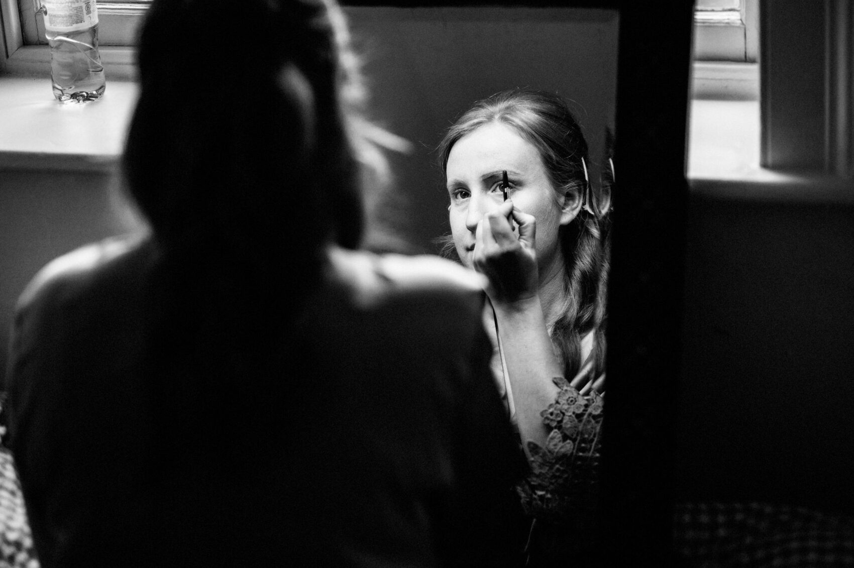 Bridesmaid applies makeup in mirror