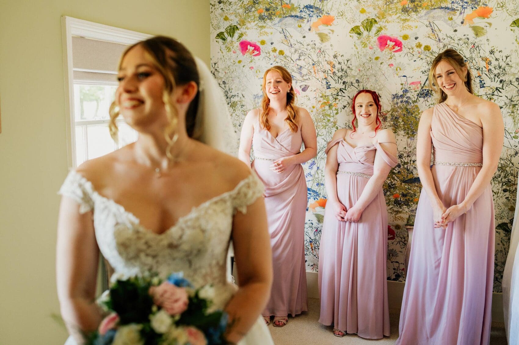 Brides maids laugh at dads reaction to the wedding dress