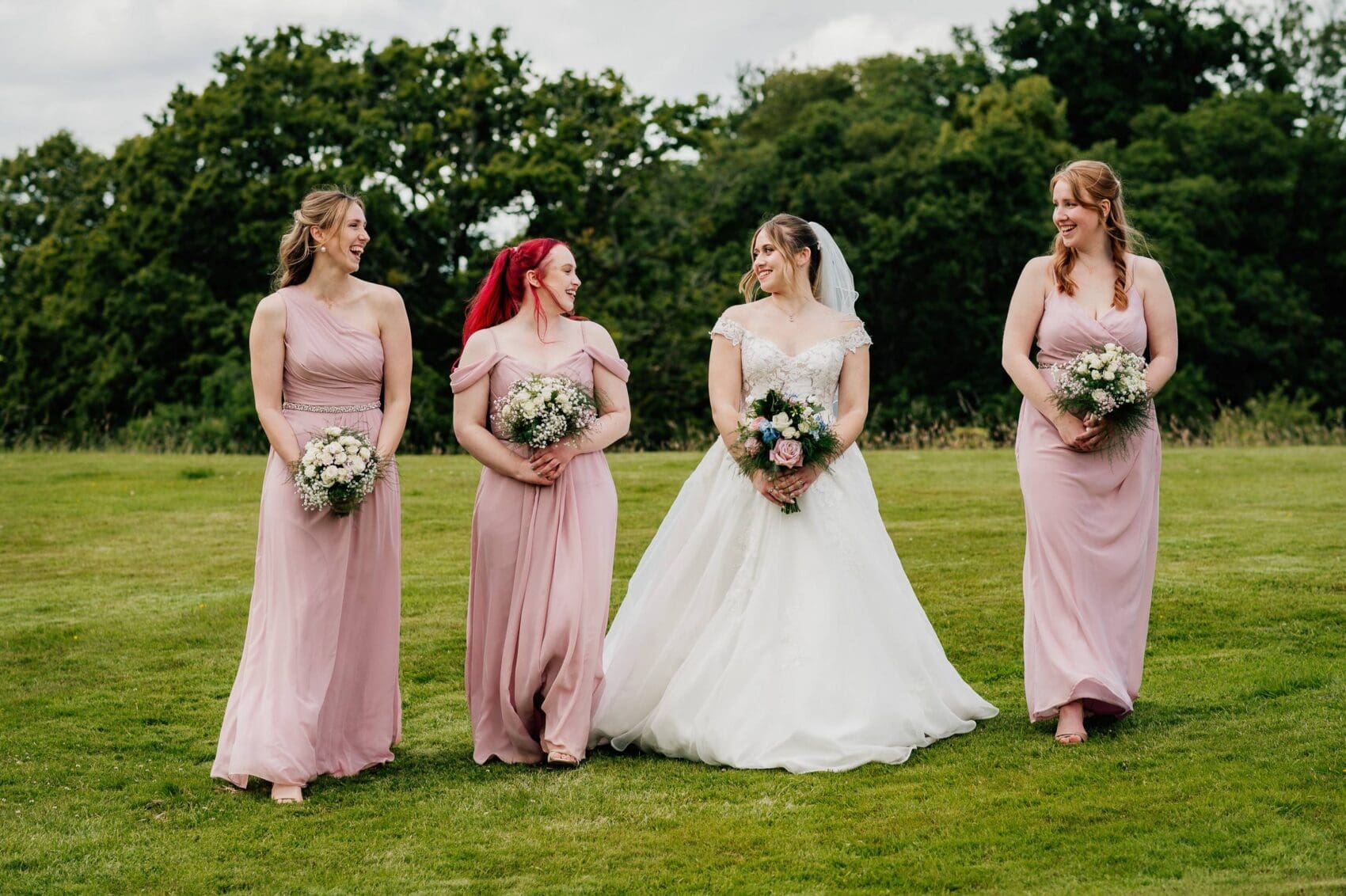 Bride and bridesmaids walk the lawn at Hale Park House Wedding