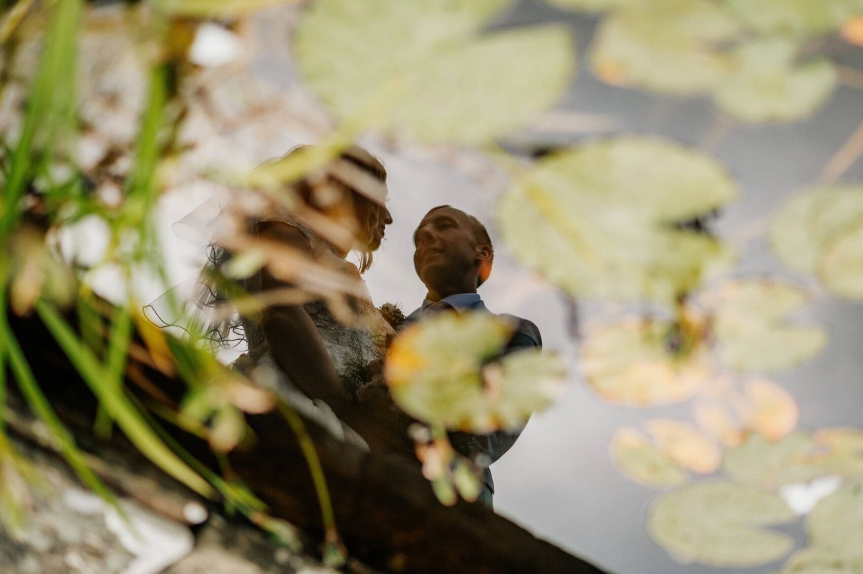 bride and groom refelcted in teh pond at Hale park house