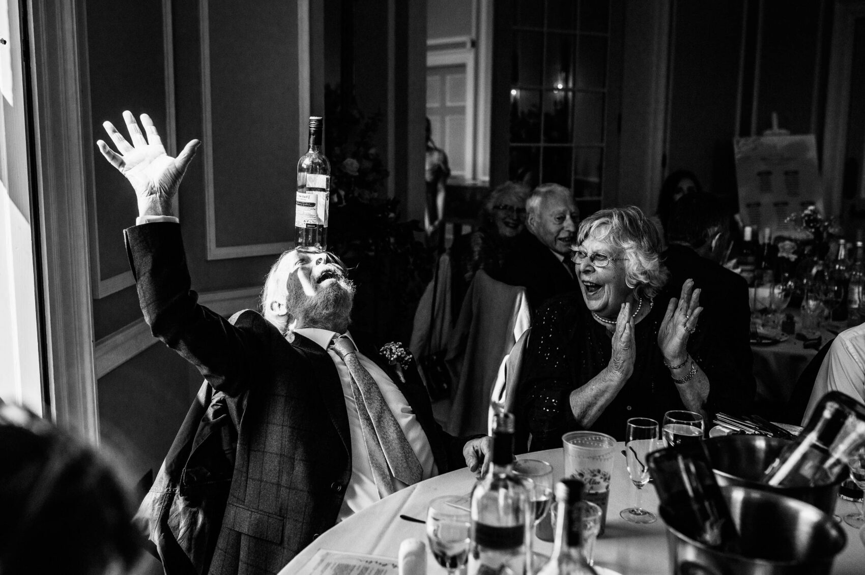 man balances wine bottle on head at Hale Park House Wedding