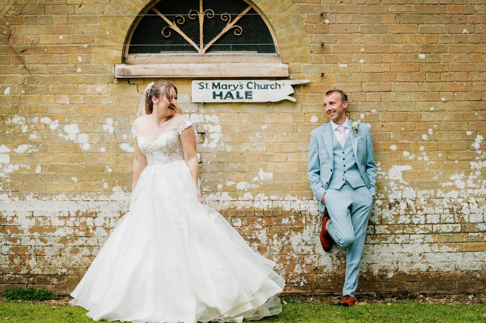 bride and groom by the sign for St Marys church in Hale