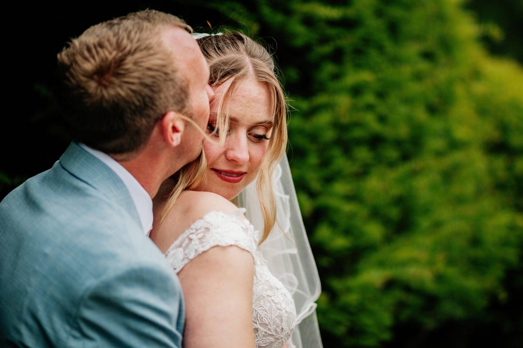 bridal and groom embrace by the pond at Hale Park House Wedding