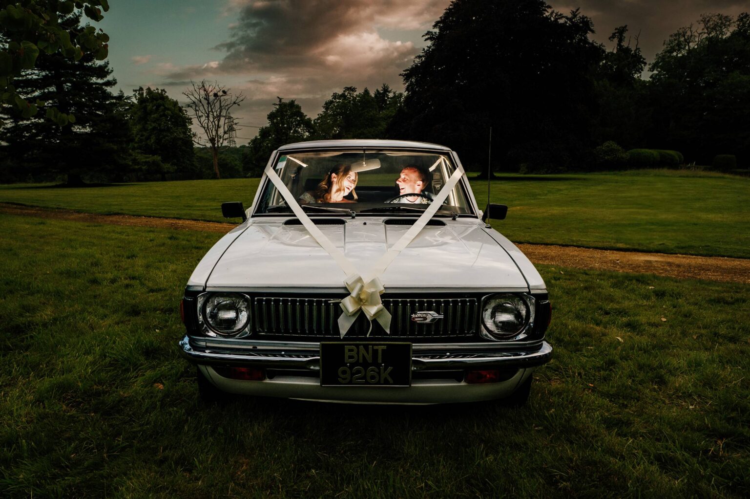 Bride and groom in their wedding car at Hale Park House Wedding lit with interior light