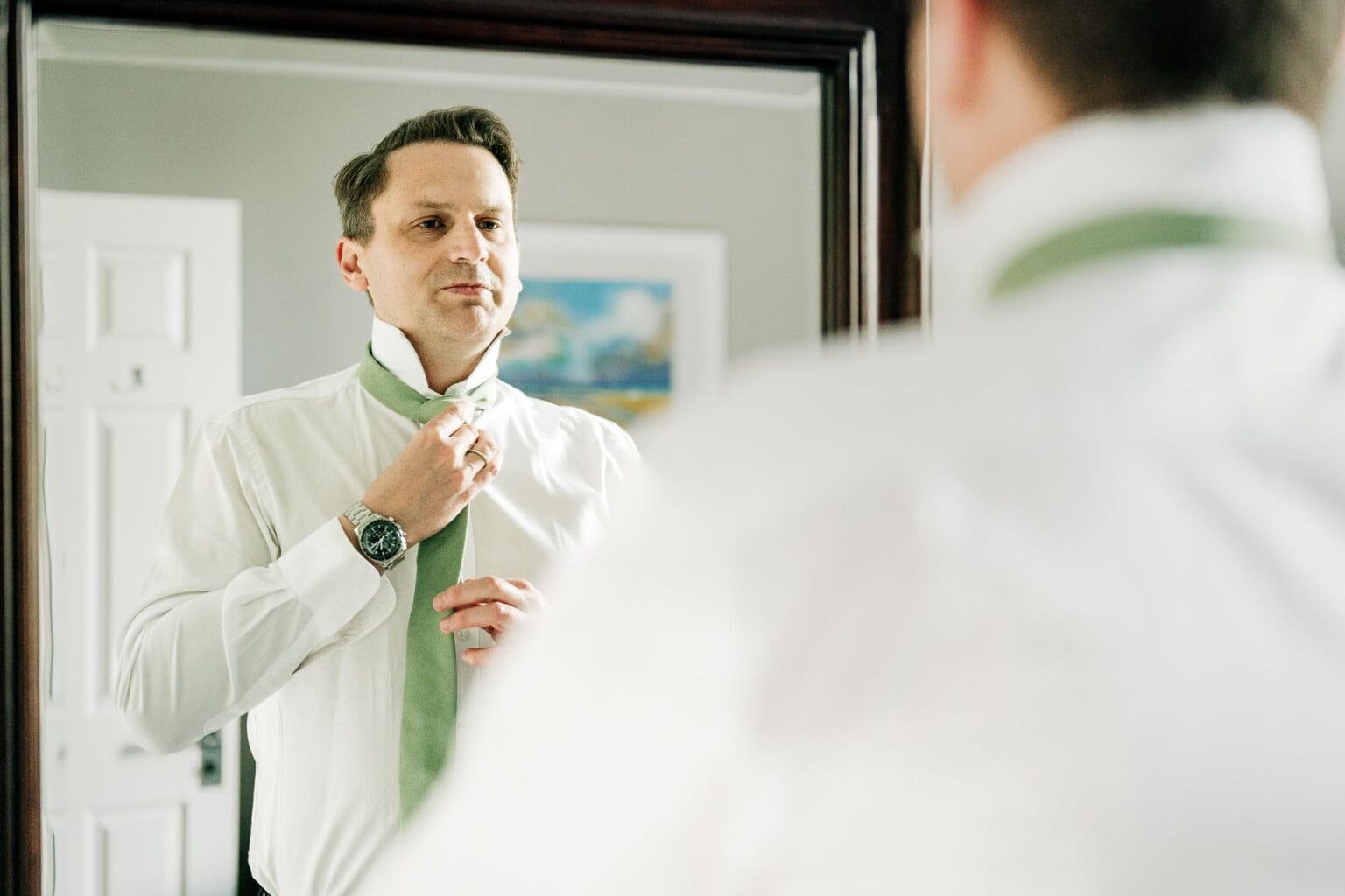 Best man adjusts his tie at River Cottage wedding