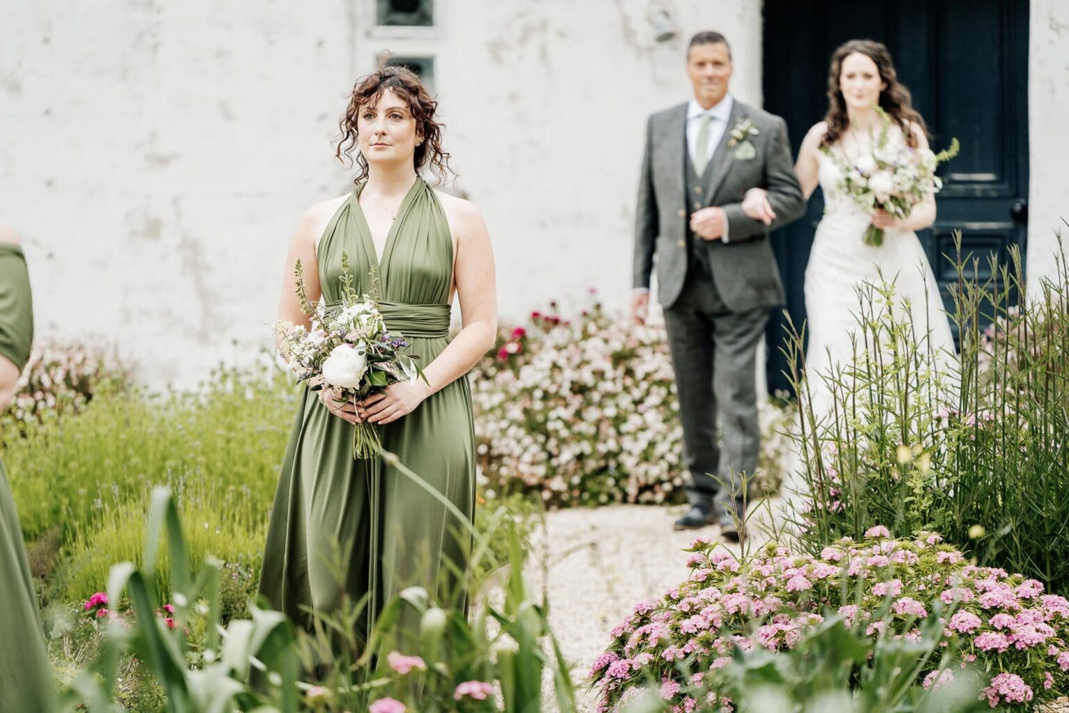 Brides sister walks in front of her dad and sister at River Cottage wedding