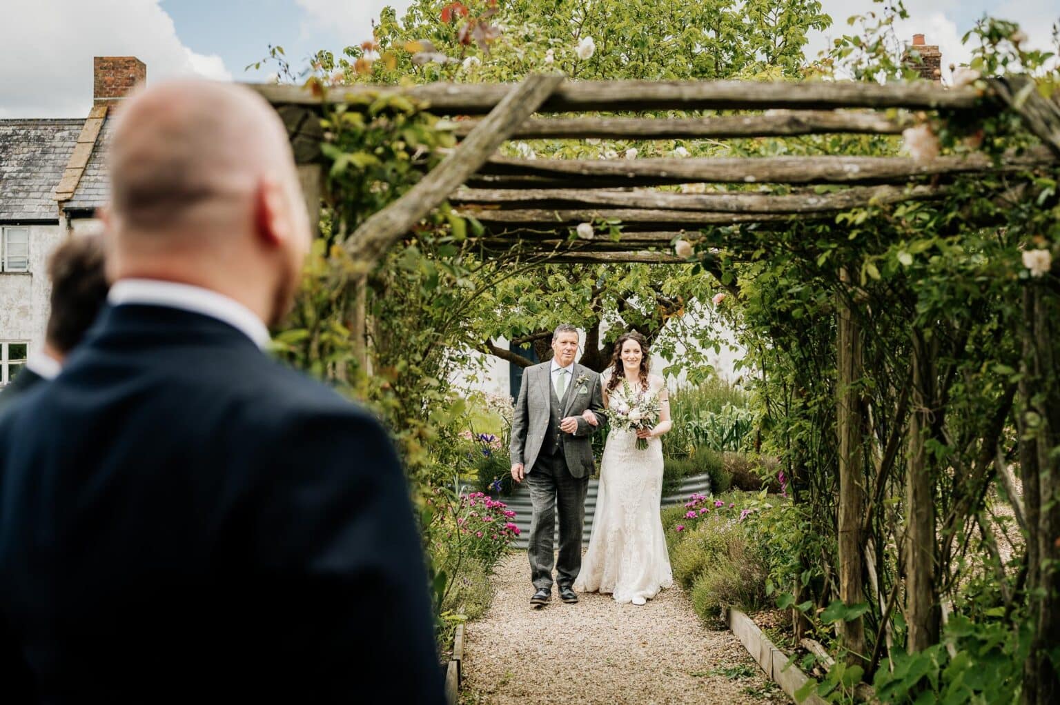 groom watches the bride walk the aisle in the kitchen garden at River Cottage wedding