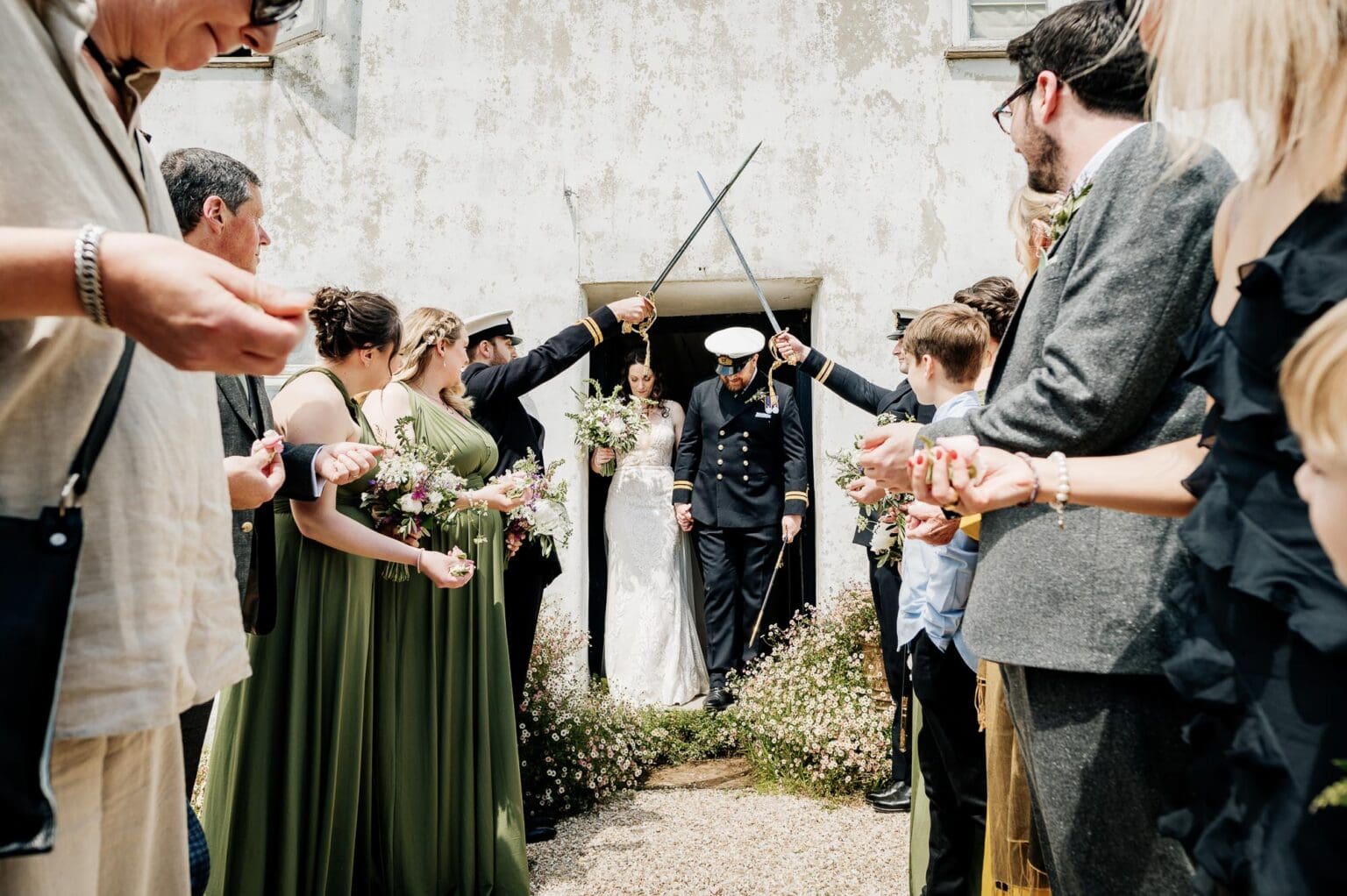 Exiting the cottage to a sword arch at River Cottage garden wedding