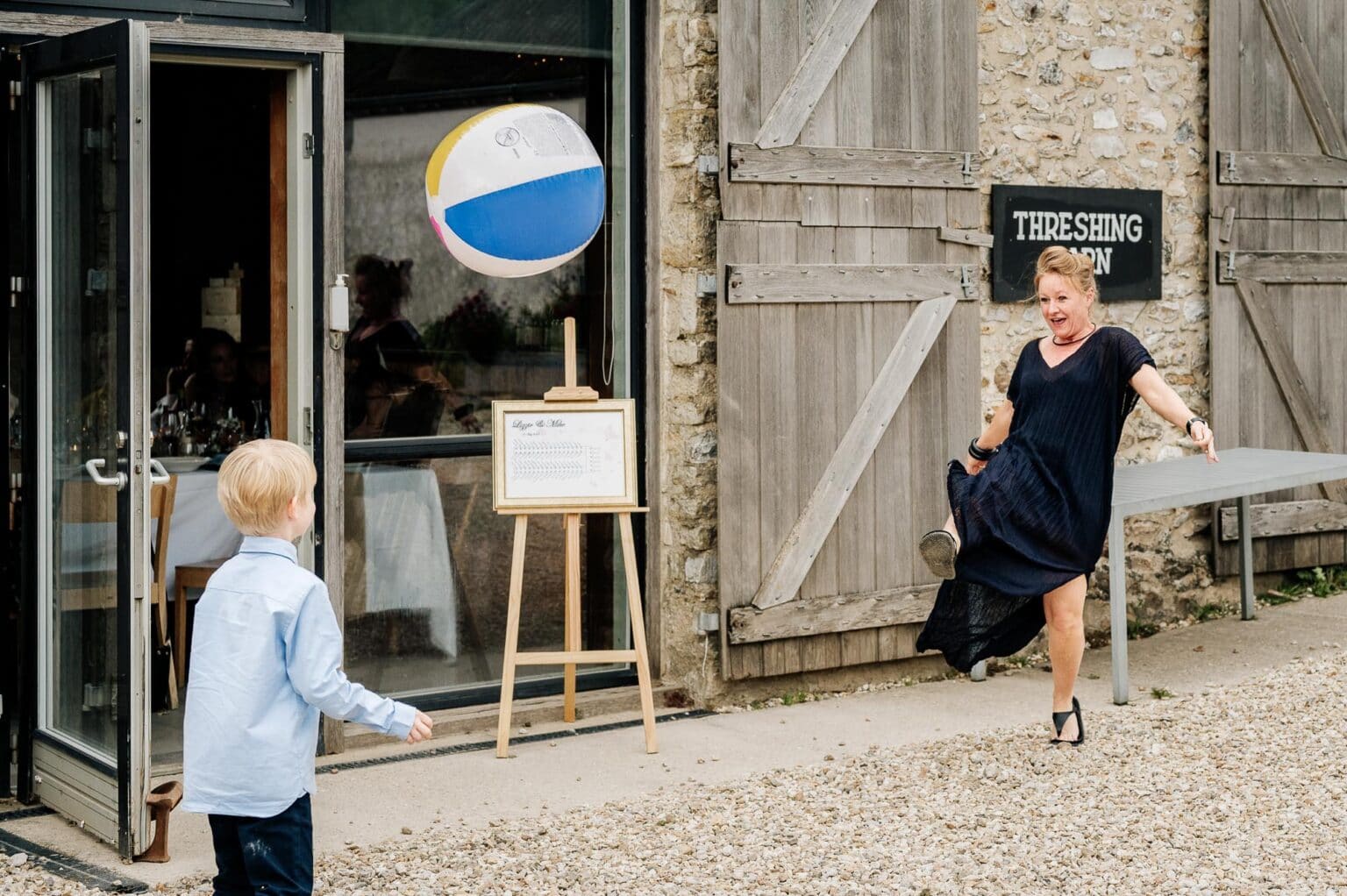 Boy playing with a large inflatable ball in the courtyard at River cottage HQ wedding