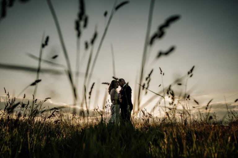 Bride and groom in sillouette against the sunset in the meadow