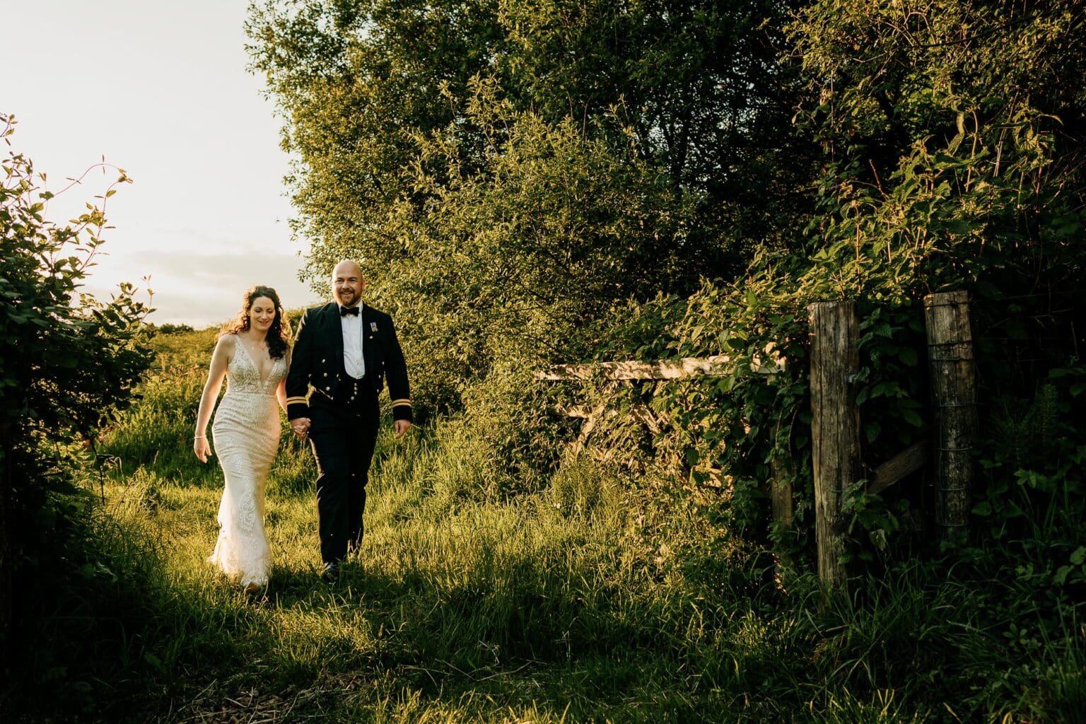 bride and groom walk through the grass at River cottage HQ wedding sunset