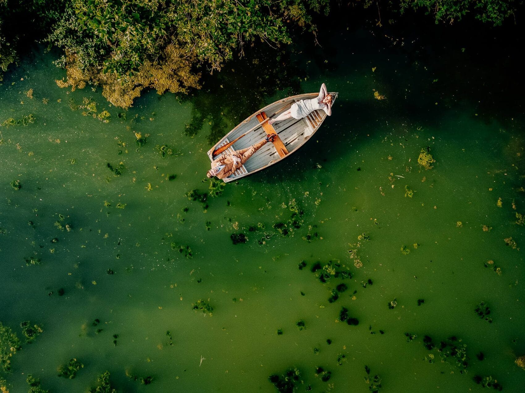 Bride and groom float on a pond