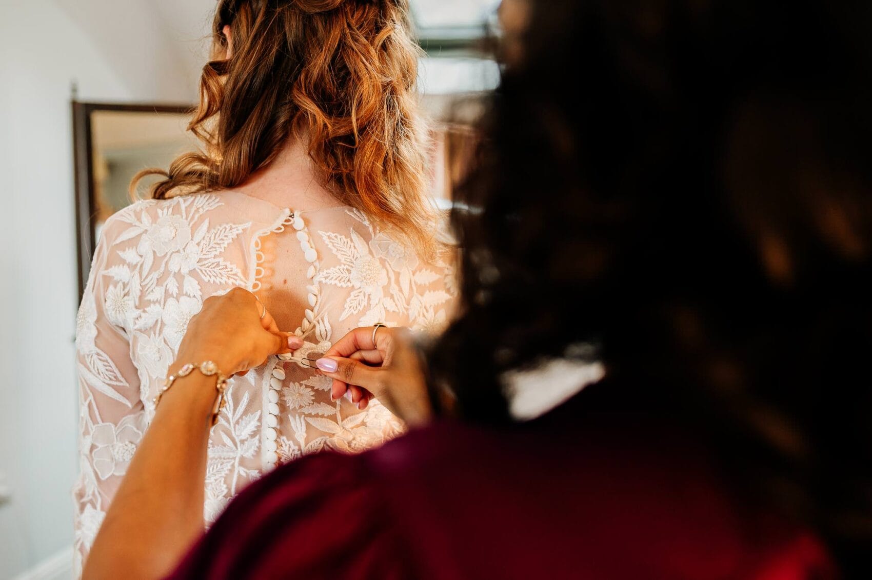 Bride having her dress buttoned from the back at Owlpen Manor weddding