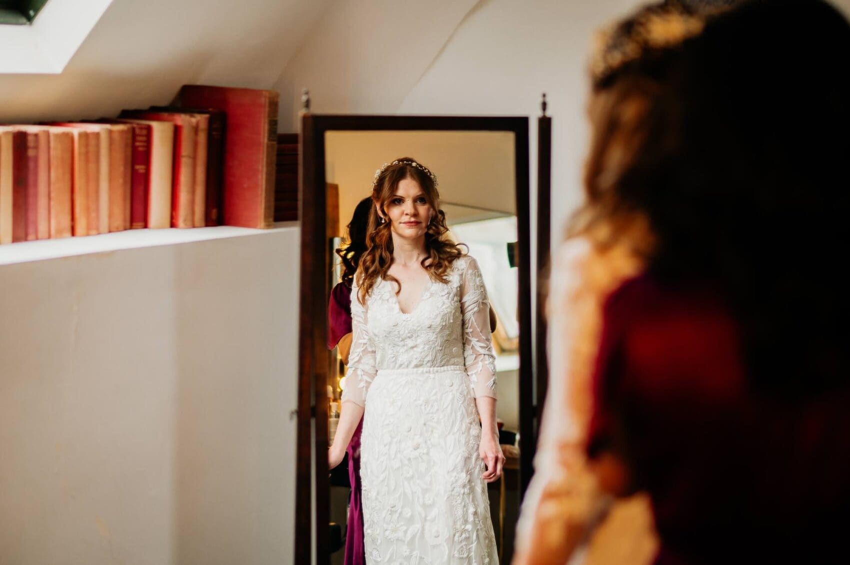 Bride looks in the mirror after putting on the wedding dress at Owlpen Manor weddding