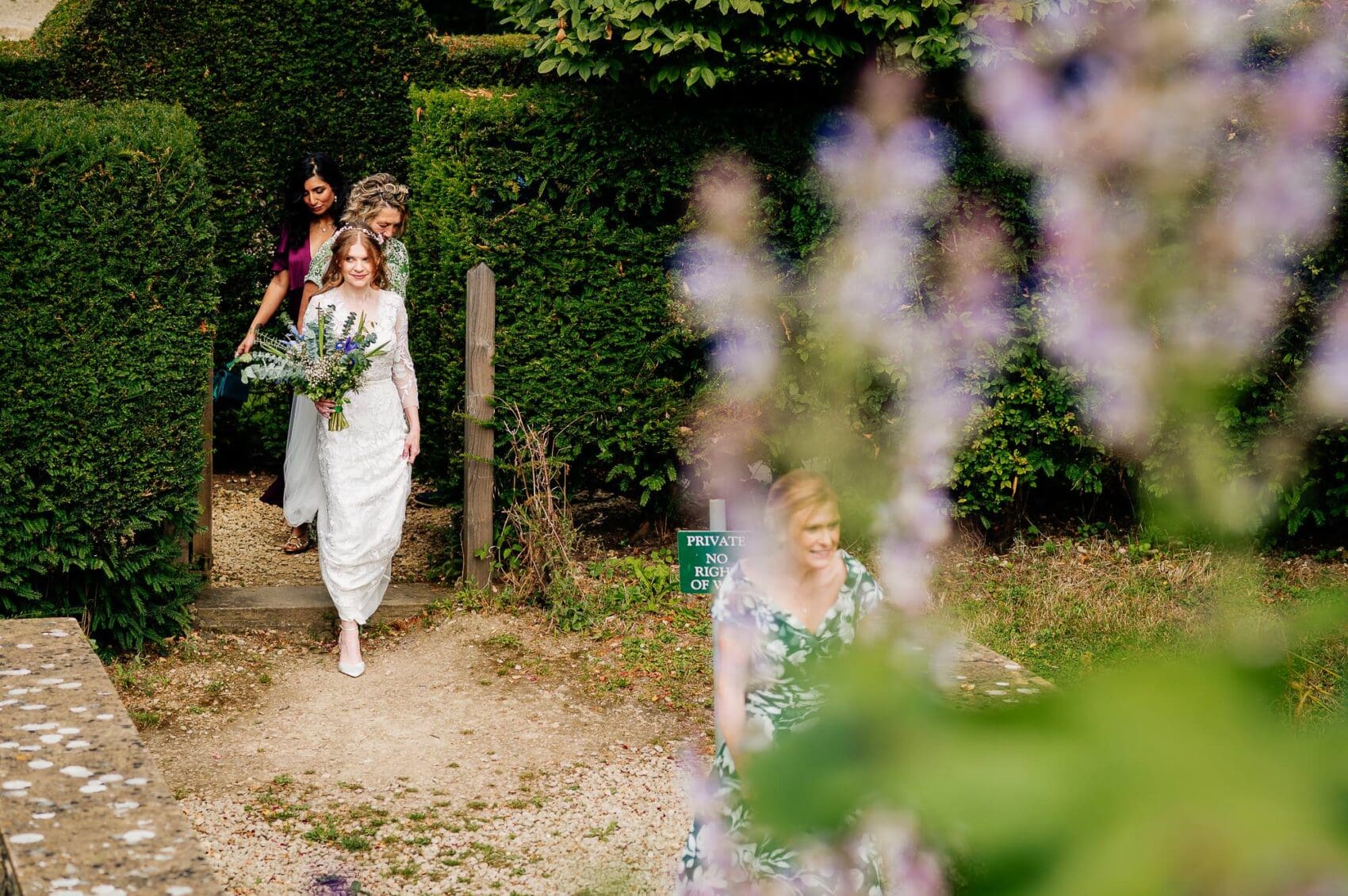 The bride walking from the manor house to the ceremony on the lawn at Owlpen Manor weddding