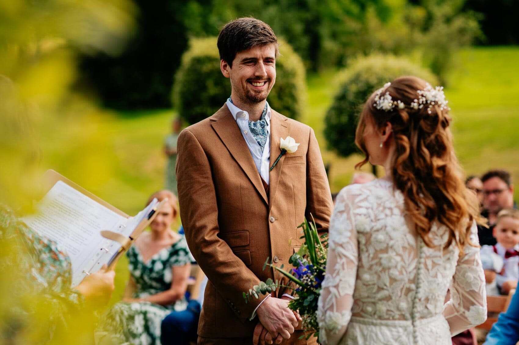 Happy groom smiles at his bride during the ceremony