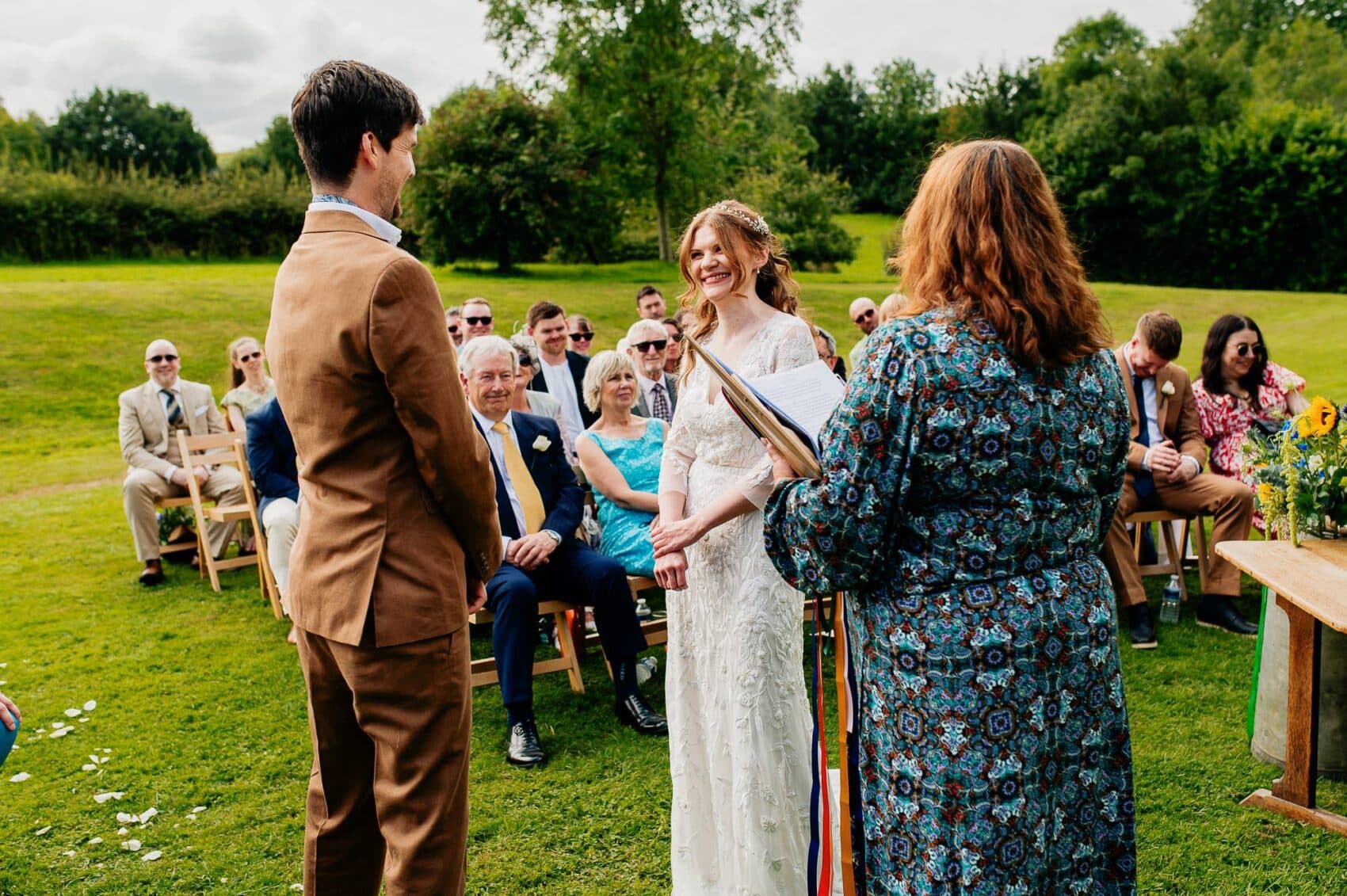 Bride smiles at the groom at the outdoor ceremony