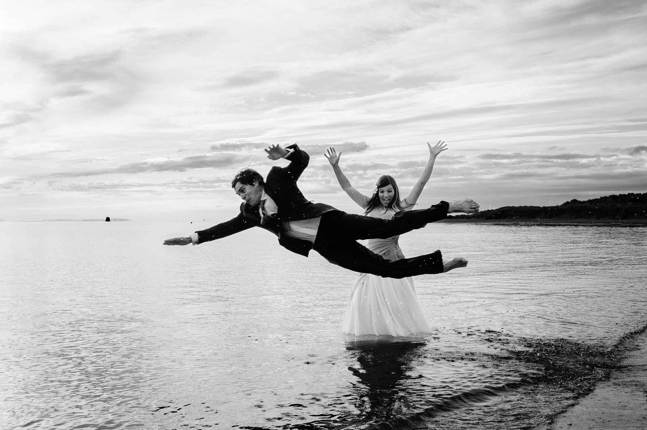 Groom jumps into the sea at Studland bay in Dorset infront of his bride