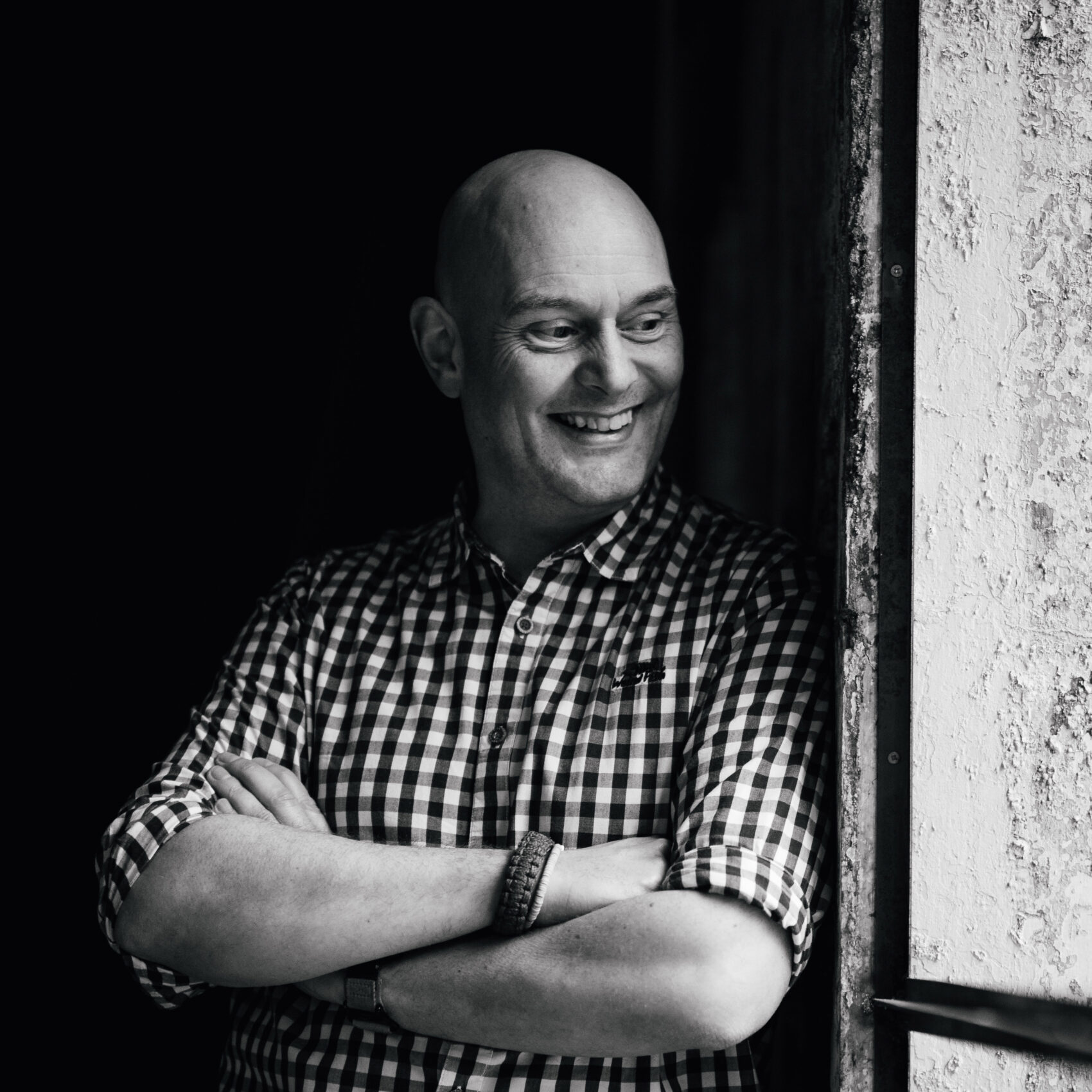 Photographer, Nathan Eames in Black and white leaning on a wall