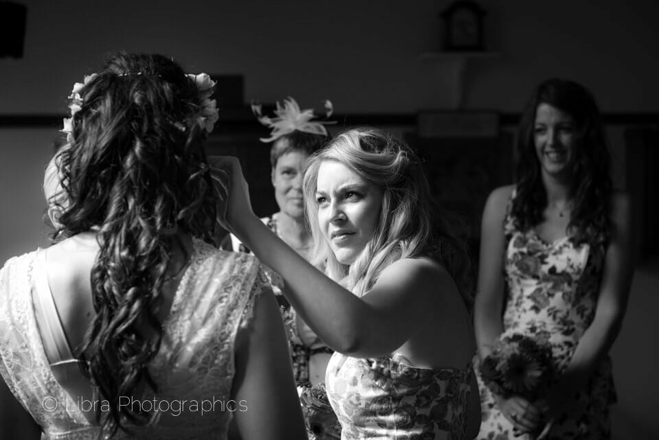 Bridesmaid adjusts brides hair in B&W