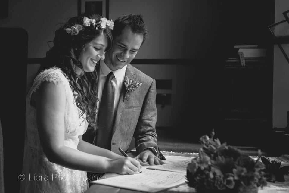 Bride and groom sign the register in B&W