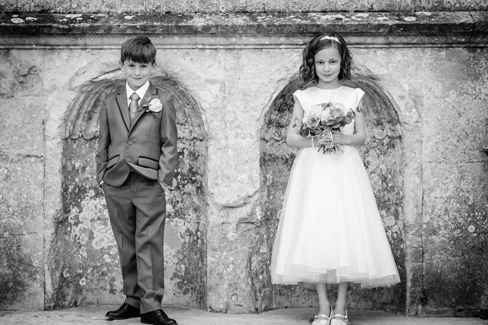 Pageboy and flower girl pose infront of lulworth castle in black and white